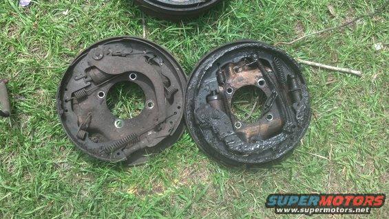 Two used brake drums with brake shoes and springs, lying on grass