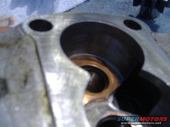 Close-up of a metallic engine part with circular openings and a brass-colored inner ring