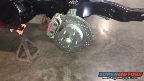 Car brake assembly with drilled rotor and Baer caliper, supported by jack stands