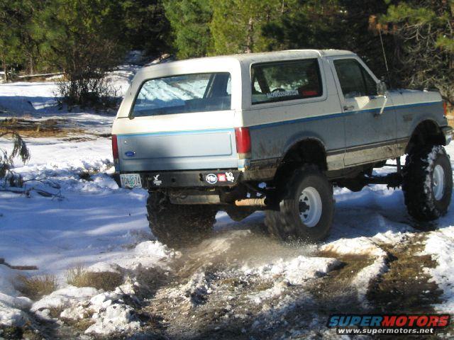 Ford Bronco with large tires driving on a snowy trail