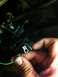 1995 Ford Mustang - A hand holds a green wire near the brake light switch wiring harness.