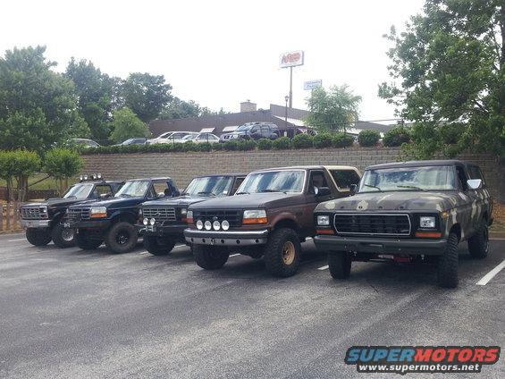 Five Ford Bronco SUVs parked in a lot, one with camouflage paint