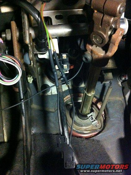 Close-up of brake light switch wiring and steering column components under dashboard