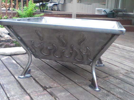 Metal fire pit with flame cutouts on a wooden deck