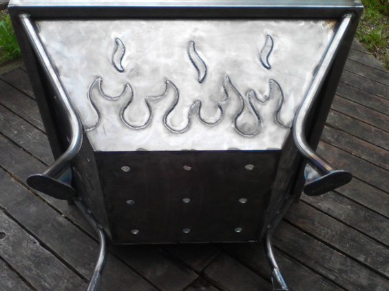 metal fire pit with flame cutouts on the side, sitting on a wooden deck