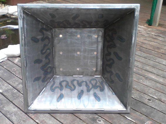 Interior view of a square metal fire pit with decorative flame-like patterns