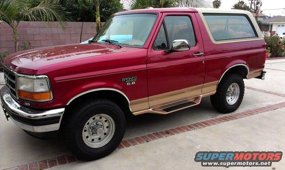 Red 1994 Ford Bronco with tan trim and running boards, parked on a concrete driveway