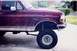 1992 Ford Bronco - Maroon 1992 Ford Bronco shows its front passenger side with aftermarket wheels and suspension modifications.