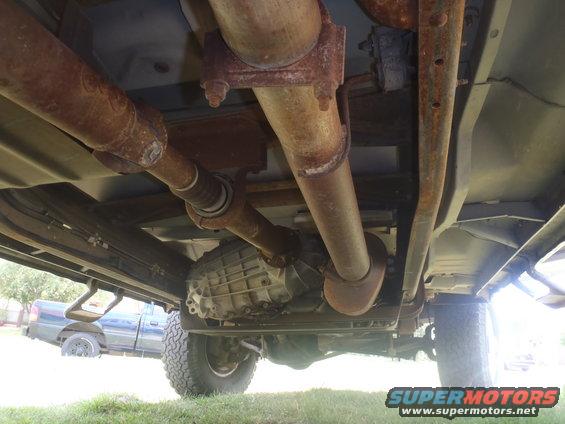 Underside view of truck drivetrain with a second truck in background