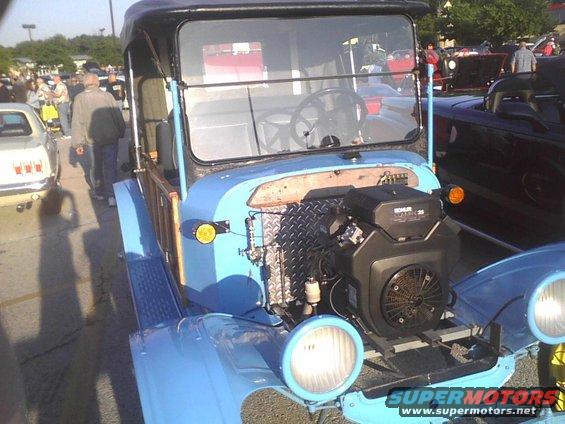 Custom light blue truck with a Kohler engine visible in front. Other vehicles and people are in the background
