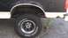 1993 Ford Bronco - This image shows the rear wheel well and tire of a black and white truck, with visible rust around the wheel arch.