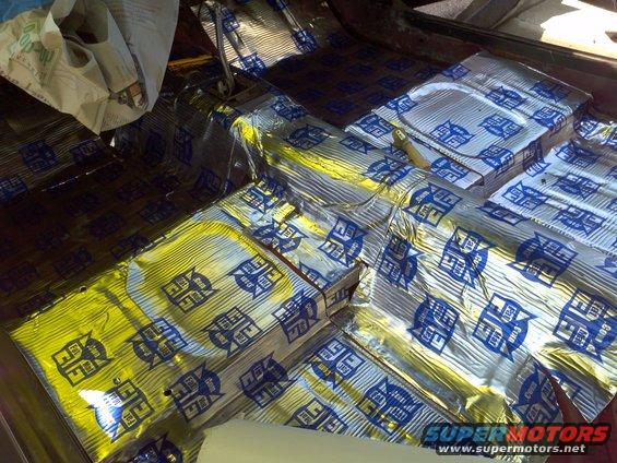Car floor covered in sound deadening material with blue logos