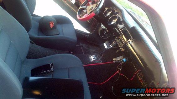 Interior view of a vehicle with blue seats, a black baseball cap, and exposed wiring