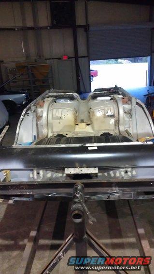 car body stripped down and on a stand, looks like it's being restored