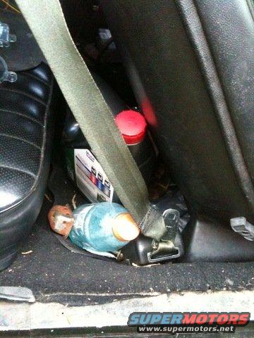 Car interior with seatbelt, bottles, and a small object on the floor