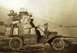 1912 Ford Model T - A heavily laden vehicle, possibly a truck, is parked near a body of water with sailboats in the distance.