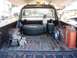 1979 Chevrolet C/K Pickup - The bed of a pickup truck is filled with various items, including a spare tire, winch, and fuel containers.