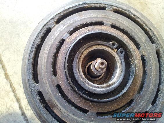 Close-up of a worn air conditioning compressor clutch with visible dust and debris