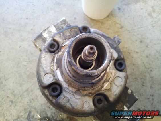 Close-up of a dirty, metallic automotive part with visible bolts and a central shaft