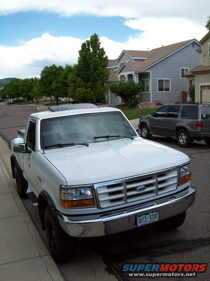 1994 Ford F-150 parked curbside, front grille and headlights visible. Another SUV is parked behind it