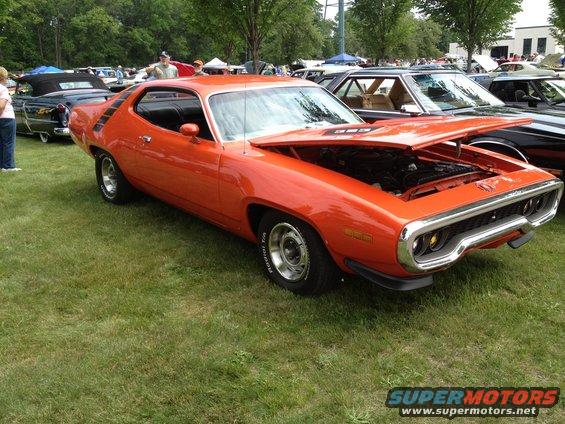 Orange 1971 Plymouth Road Runner with hood open, parked on grass at a car show