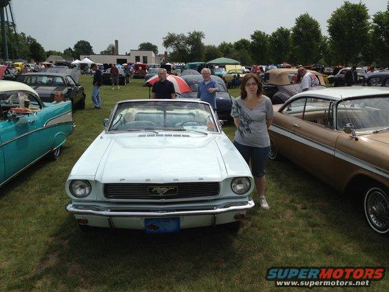 Light blue convertible Mustang with a woman standing next to it at a car show