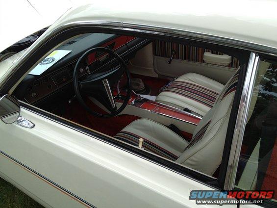Interior of a white car with striped cloth seats and wood-grain trim