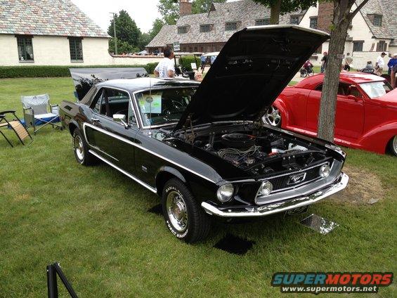 Black 1967 Ford Mustang coupe with hood open, parked on grass