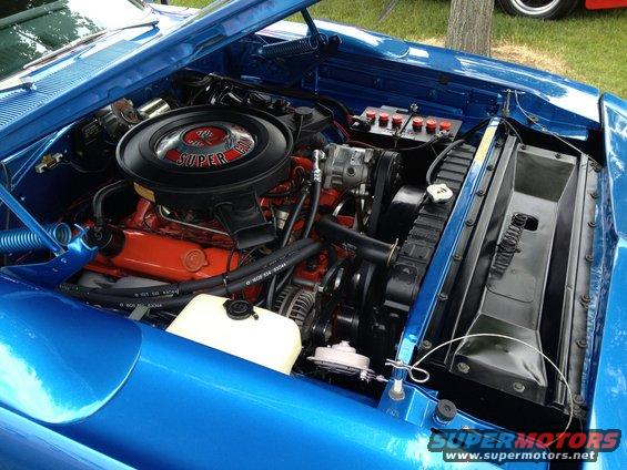 Engine bay of a blue 1969 Dodge Charger R/T with a Super Commando air cleaner. Shows V8 engine, radiator, and battery