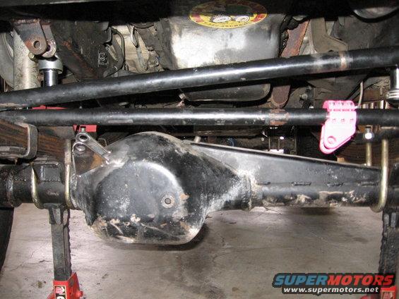Underside view of vehicle's rear axle, leaf springs, and steering linkage. Vehicle is on jack stands