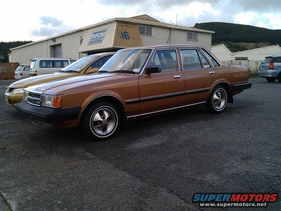 Brown sedan parked next to a gold sedan in front of a building