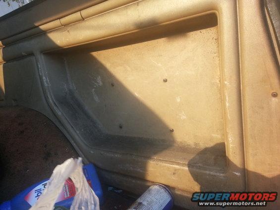 Interior paneling and cargo area with a blue bottle and a can. Supermotors.net logo visible