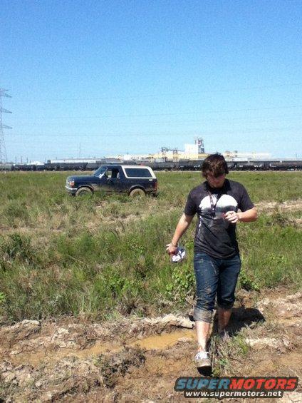 Dark blue Ford Bronco with a white top parked in a muddy field