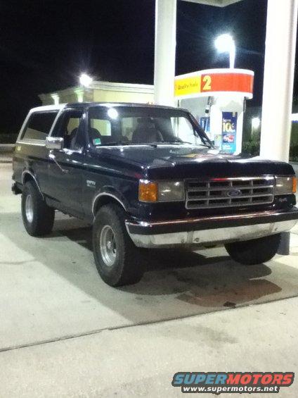 1988 Ford Bronco parked at a gas station pump at night