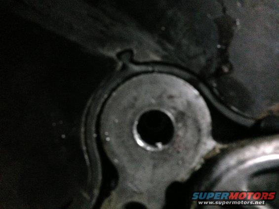Close-up of a metal engine component with a circular hole, showing wear and grease