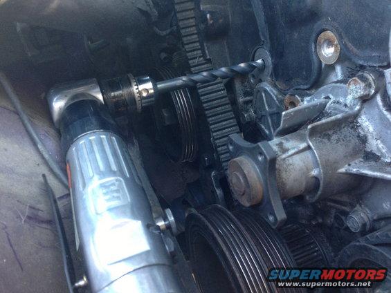 Engine timing belt with a drill bit inserted into a pulley