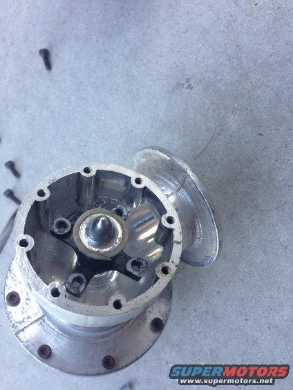 Aluminum automotive part with bolts and a central cone, on a concrete surface