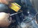 1996 Ford Probe - A person is using a tool to work on the timing belt of an engine while holding a can of oil.