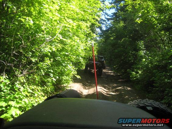 Front view of a Jeep Wrangler on a dirt road, with another Jeep behind it