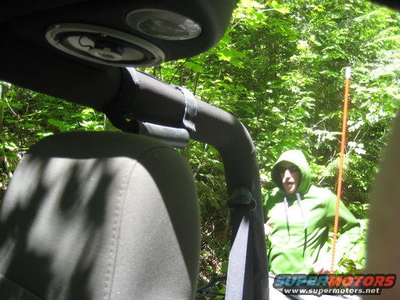 2005 Jeep Wrangler interior showing seat, roll bar, speaker, and a person in a green hoodie outside