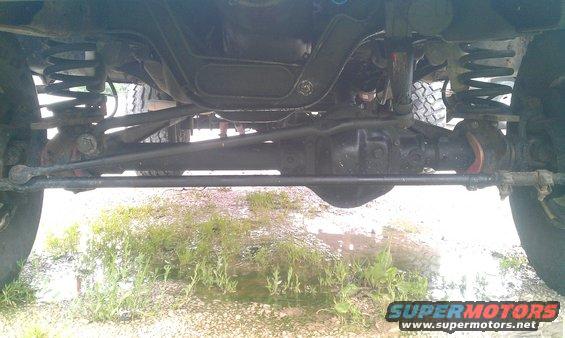 Undercarriage view showing front axle, suspension components, and steering linkage of a 4x4 vehicle