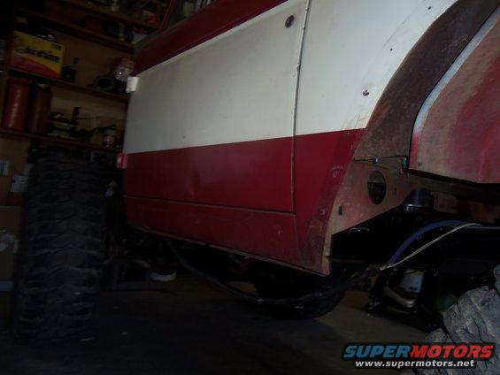 Side view of a red and white vehicle, showing a large tire and wheel well