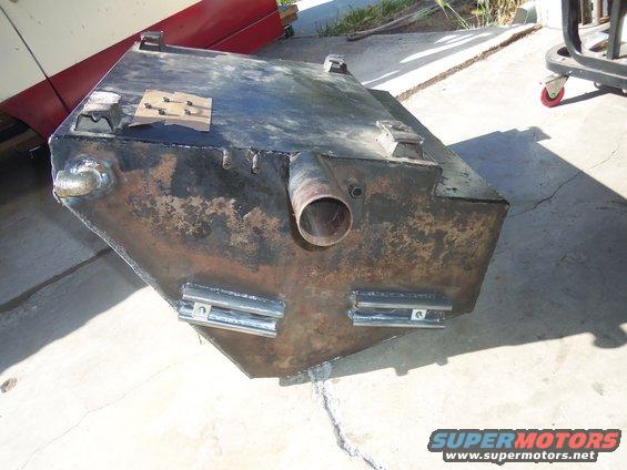 Custom metal fuel tank with welded fittings and mounting brackets, showing rust and wear