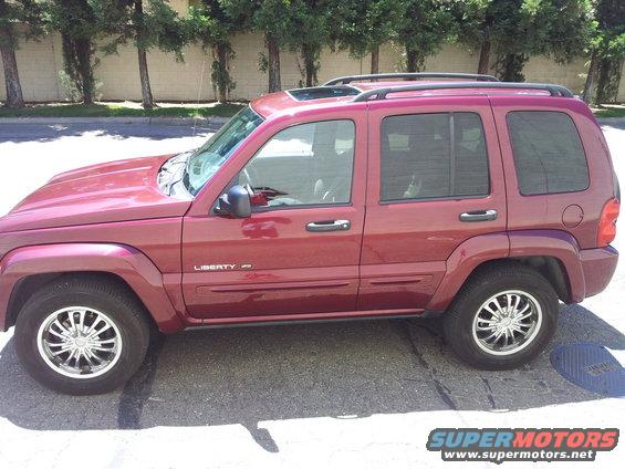 Side view of a red Jeep Liberty SUV with tinted windows and a sunroof