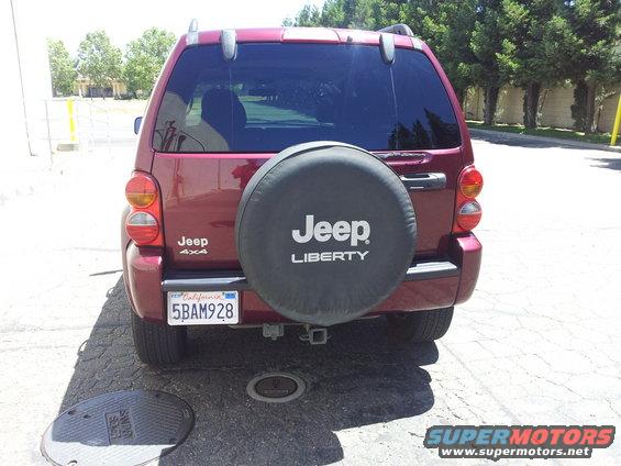 Rear view of a red Jeep Liberty with a spare tire cover. License plate reads 5BAM928