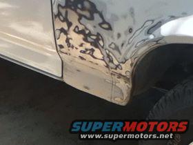 Side panel of a vehicle with body filler and primer applied, showing repair work