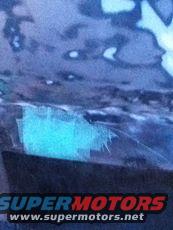 Blue repair material on dark vehicle body panel, SuperMotors.net logo visible