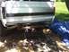 1996 Ford Bronco - The rear of a white Ford pickup truck is shown, with a trailer hitch and some tools on the ground.