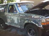 1996 Ford Bronco with hood open, showing extensive body damage and primer