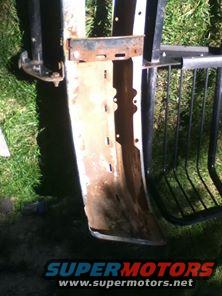 rusted metal bumper section with mounting brackets and part of a black grille